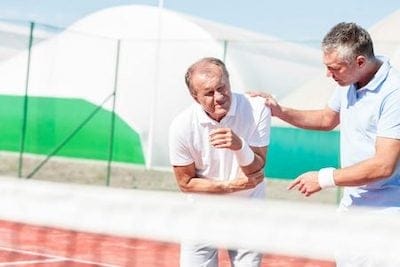 To mænd binder hinanden på en tennisbane.
